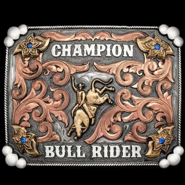 The bull riding champion belt buckle features a German Silver base, hand-engraved Copper scrolls, 4 blue CZ stones, and a bold bull rider figure.